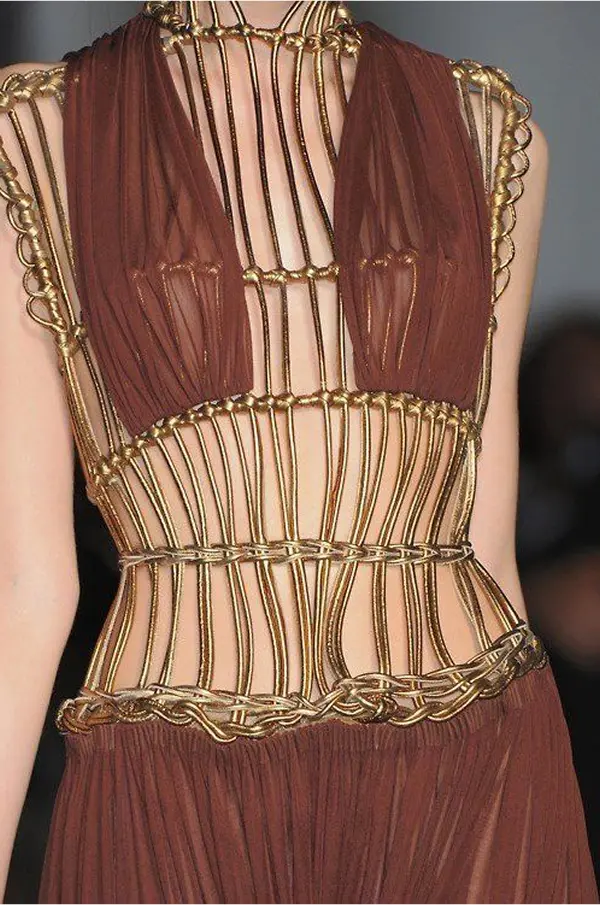 femme portant une robe terracota et dorée, tressage quadrillée laisssant apparaitre la peau sur son ventre