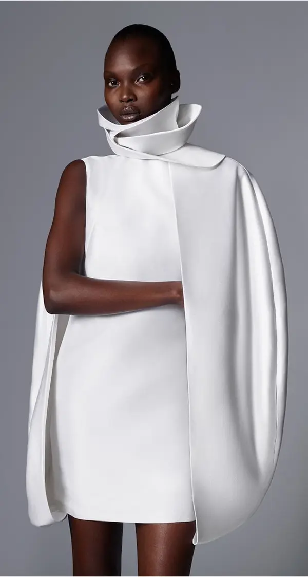 femme portant une courte robe blanche asymétrique, col remontant