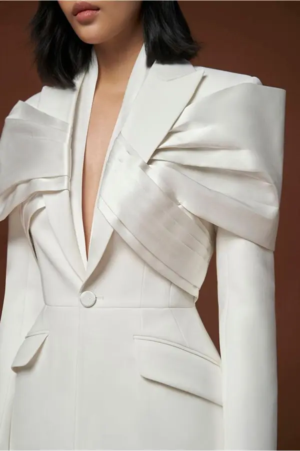 femme portant une veste de costume blanche, tissus supplémantaires au niveau des manches